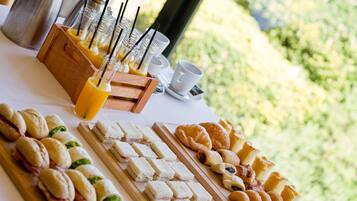 Een ontbijtbuffet met belegde broodjes, gebak en sinaasappelsap.