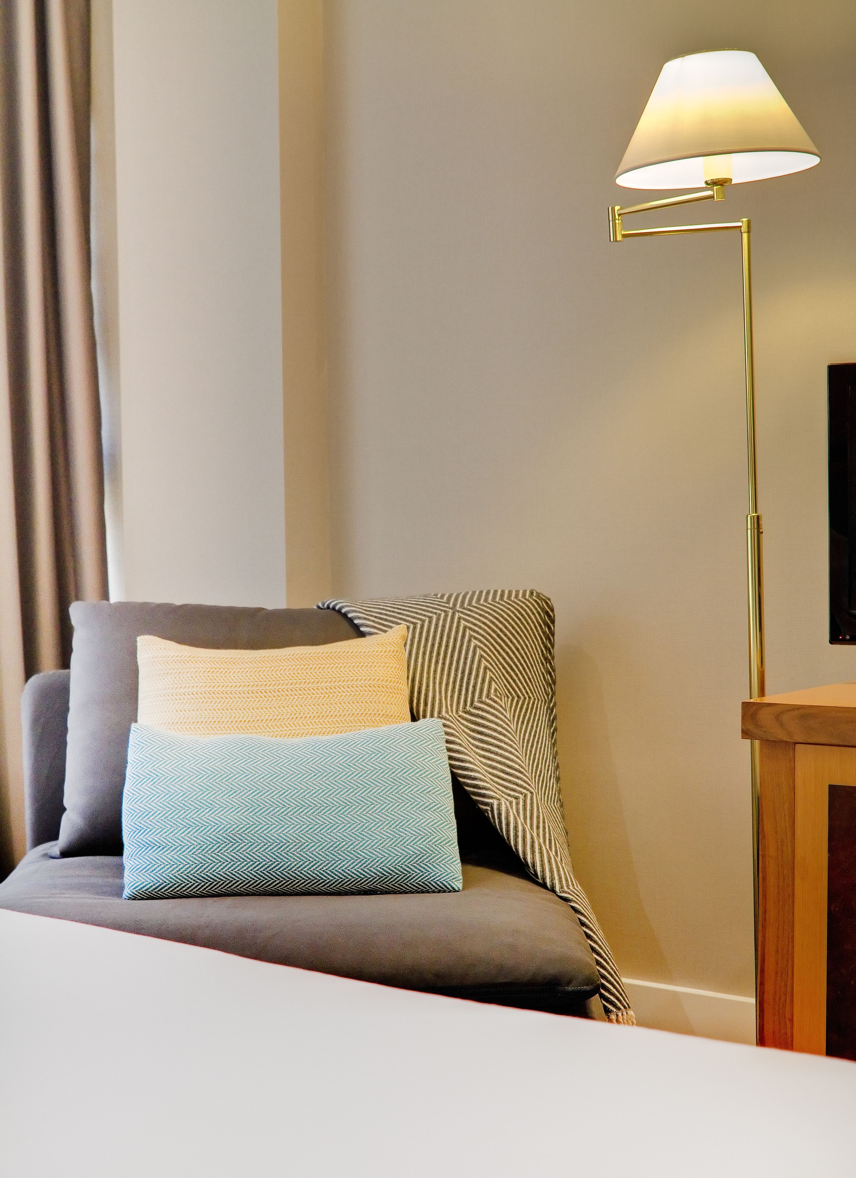 Ein modernes Hotelzimmer mit einer Couch, einer Stehlampe und einem Holztisch.