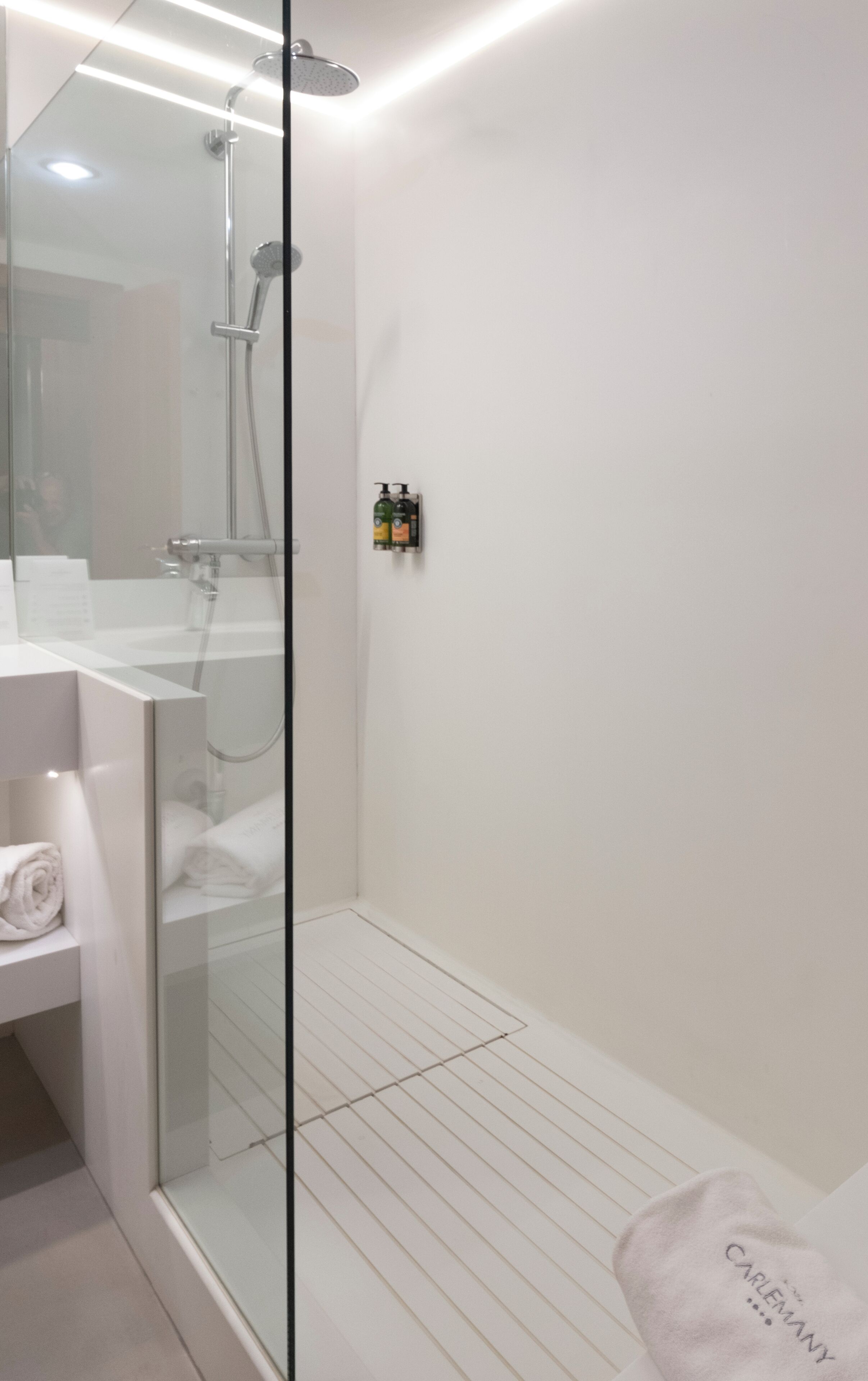 A modern bathroom with a glass shower enclosure, a white sink, and a towel rack.