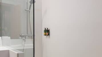A modern bathroom with a glass shower enclosure, a white sink, and a towel rack.
