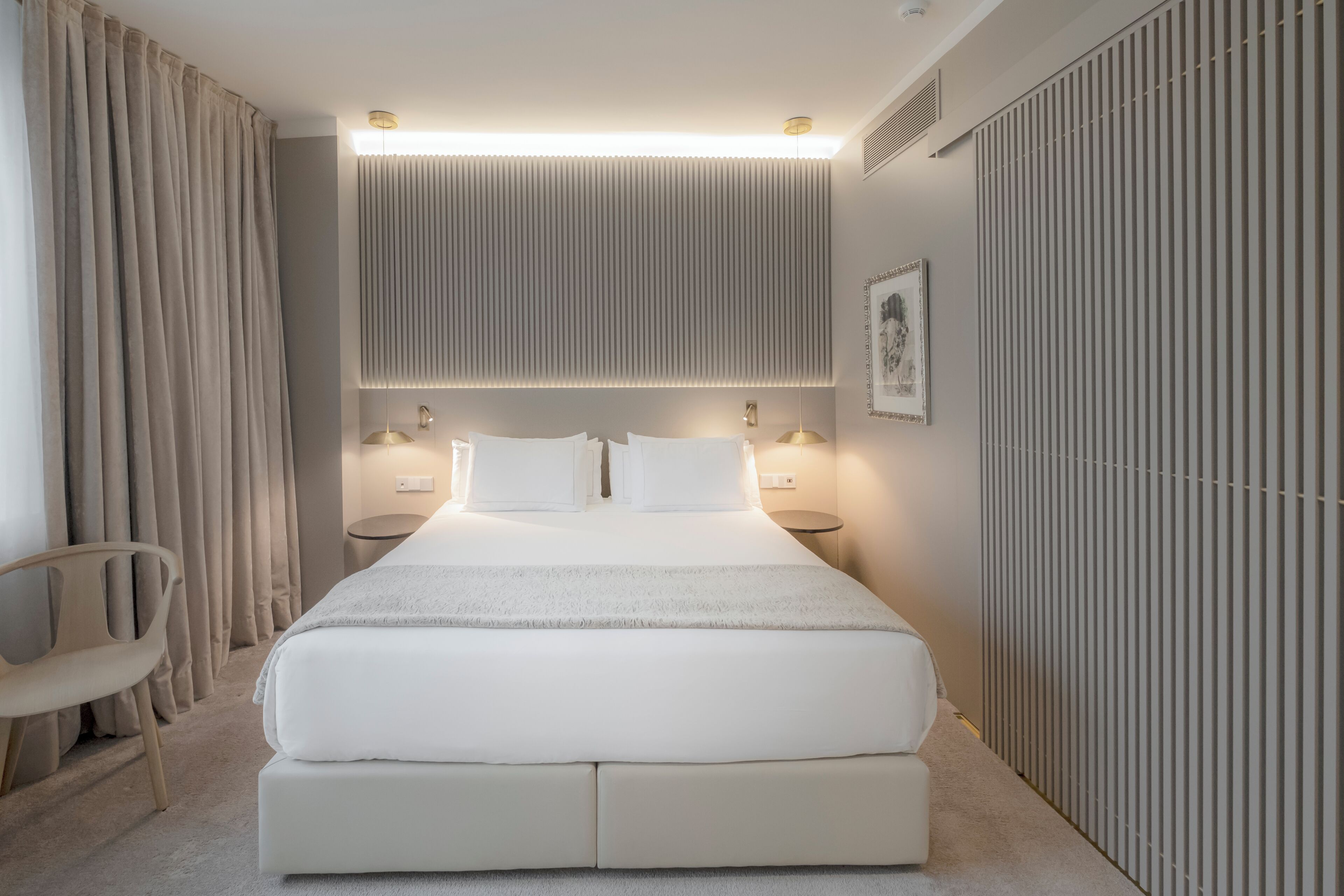 Une chambre moderne avec un grand lit, des lampes de chevet, un fauteuil et un radiateur.