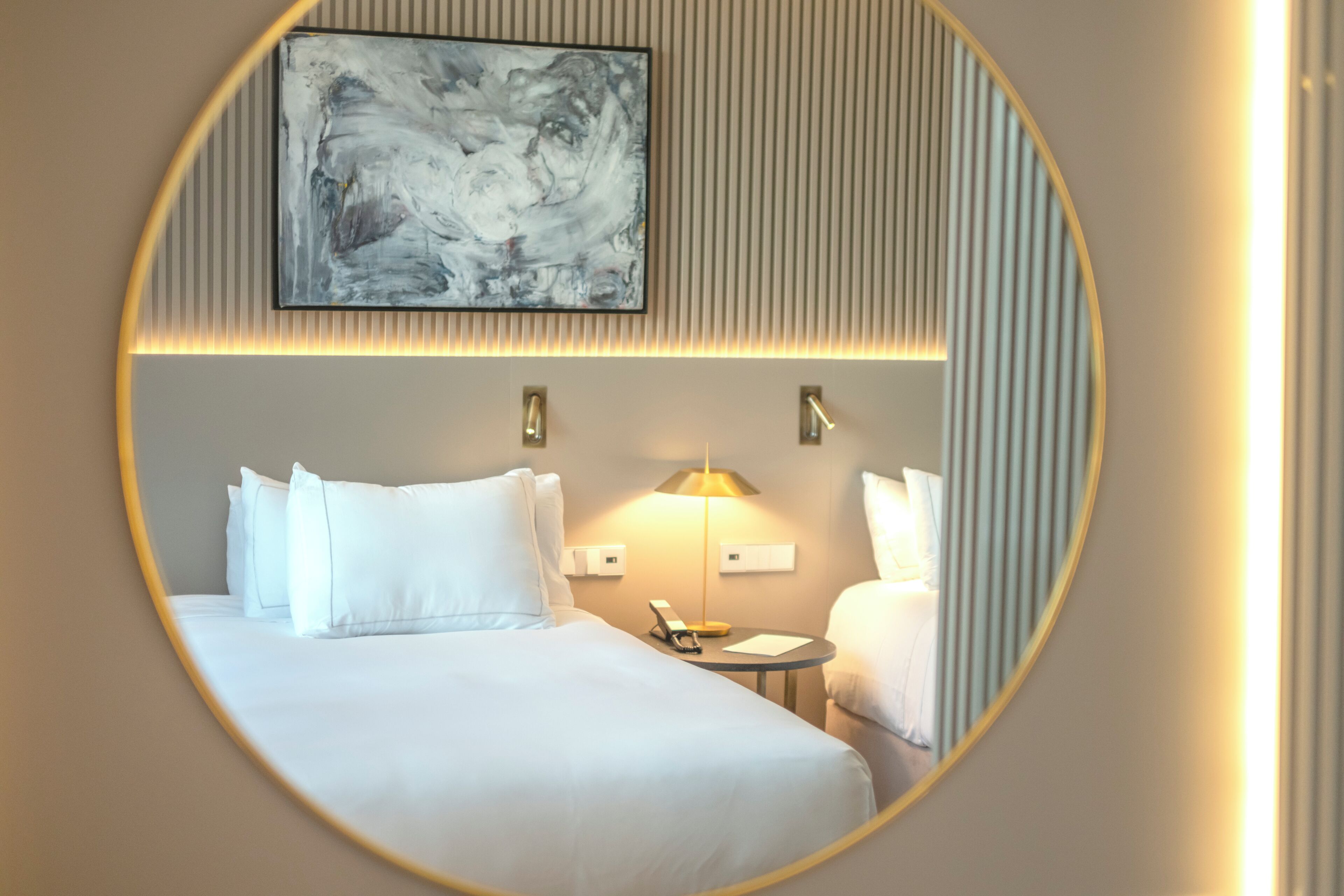 Una habitación de hotel con una cama grande, mesitas de noche, una lámpara y una obra de arte enmarcada en la pared.