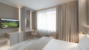 Una habitación de hotel moderna con una cama grande, un escritorio, una silla, un televisor y una ventana con cortinas.