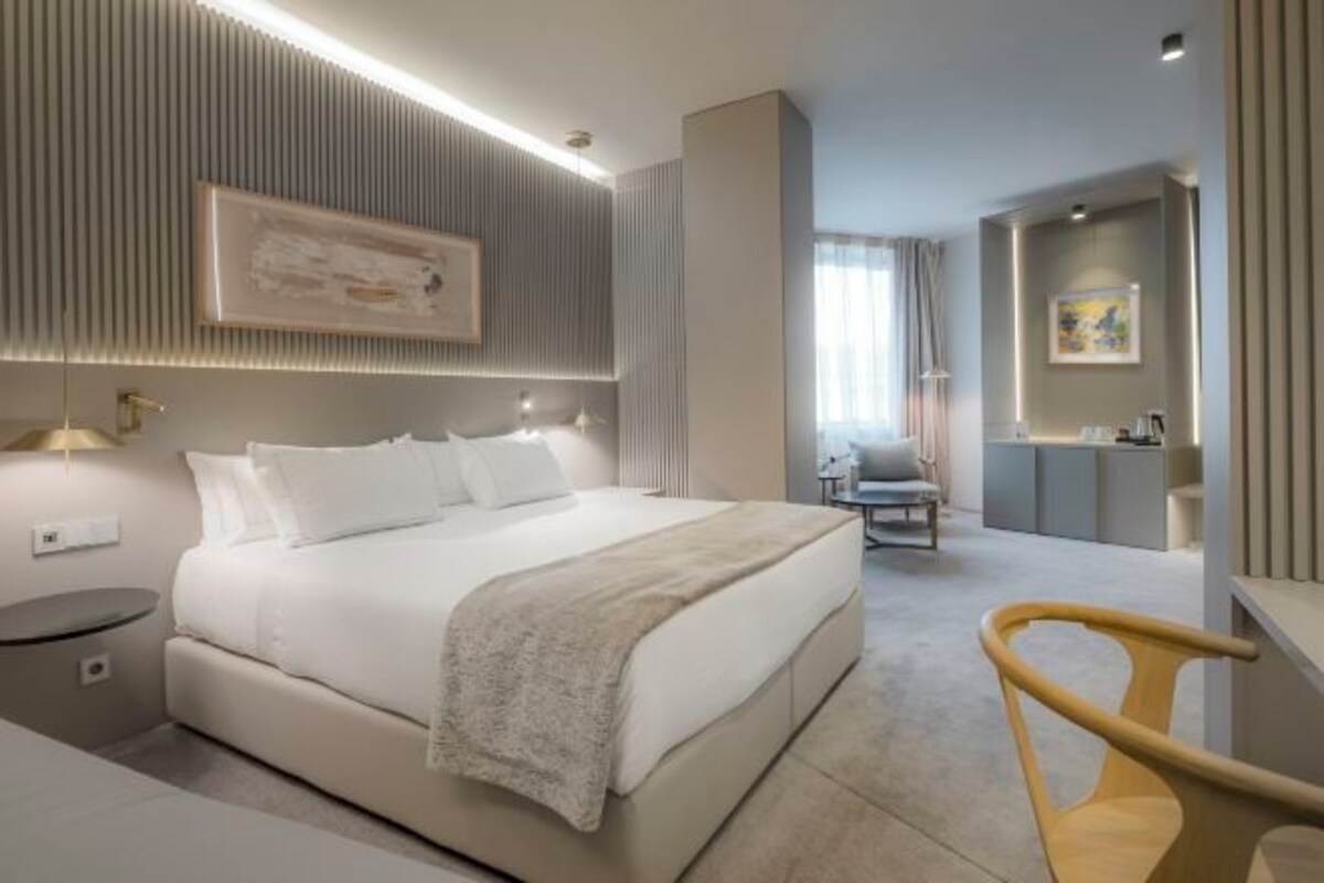 A modern hotel room with a large bed, bedside tables, a desk, and a chair.