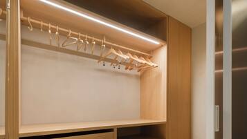 Ein begehbarer Kleiderschrank mit Holzböden, einer Kleiderstange und einer eingebauten Lampe.