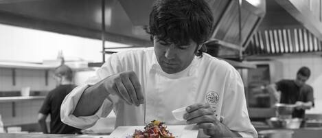 Un chef preparando un plato en una cocina profesional con superficies de acero inoxidable y equipo moderno.