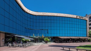 Un hotel moderno con fachada curva, zona de estar al aire libre y entrada visible.