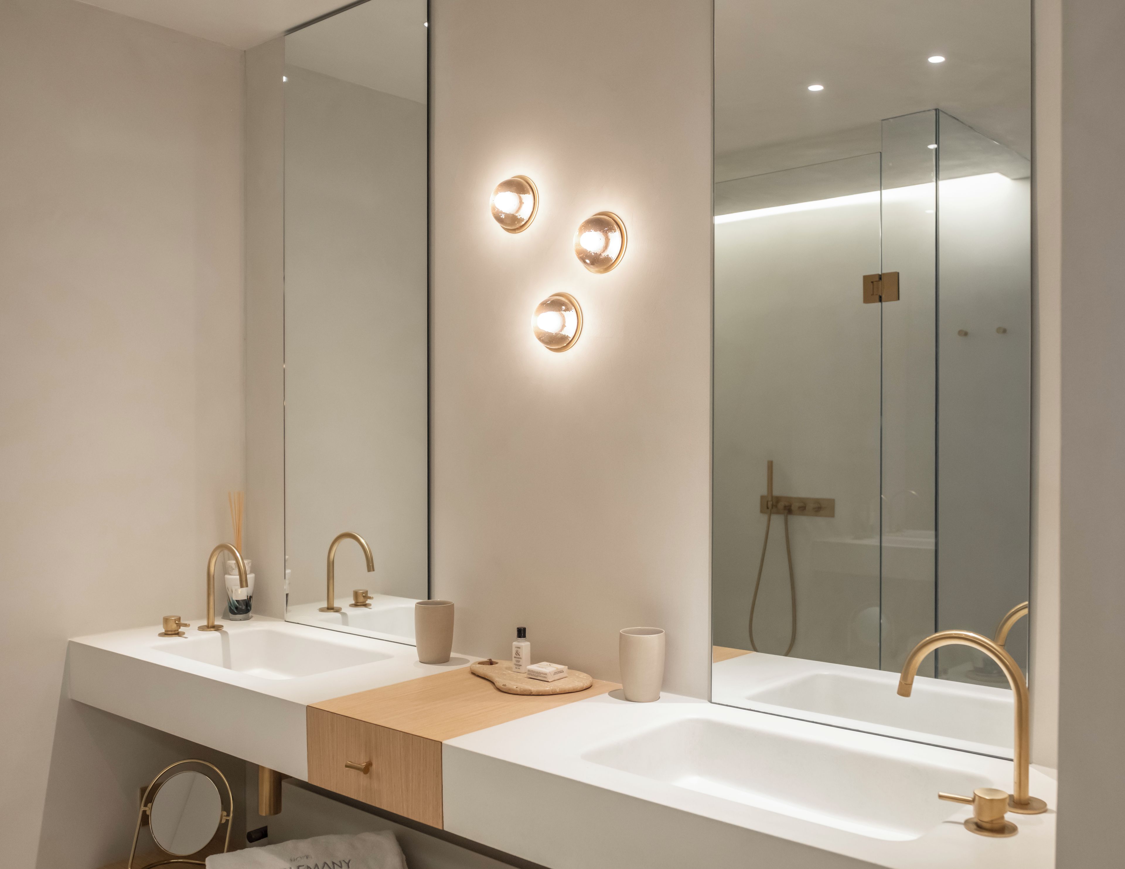 Ein modernes Badezimmer mit einem großen Spiegel, zwei Waschbecken und einer Dusche.
