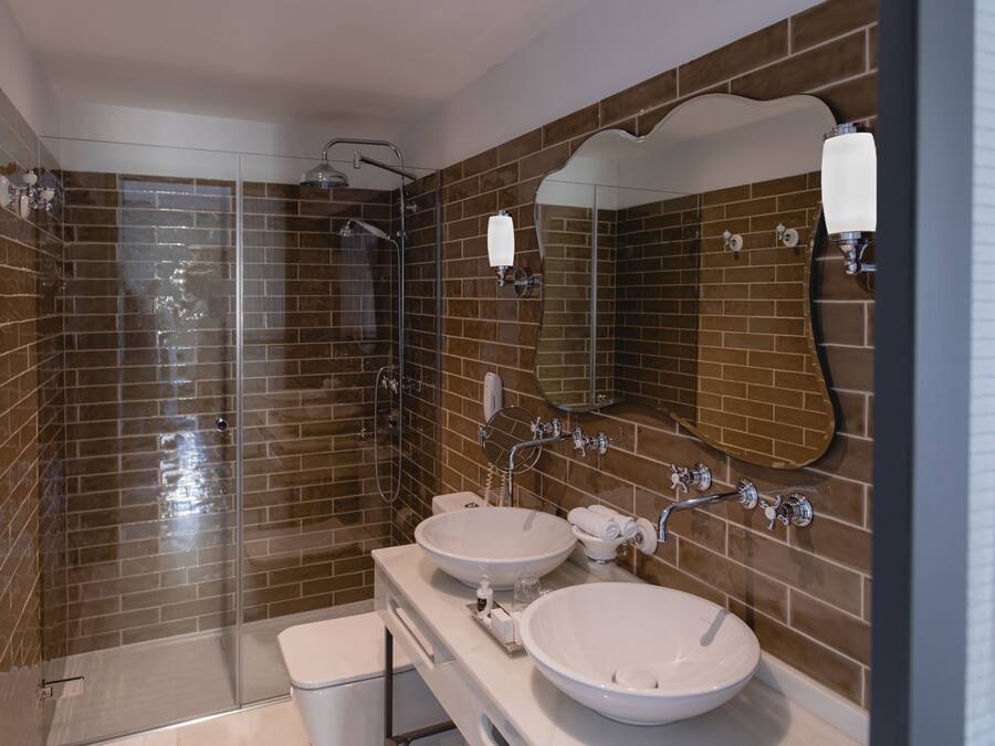 Un baño moderno con dos lavamanos, cabina de ducha de vidrio y un espejo grande.