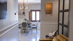 A well-lit hallway with a dining area, a sofa, and a chandelier. - Hotel Gravina 51 (Seville)