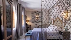 Ein Hotelzimmer mit einem großen Bett, einem Schreibtisch, einem Sessel und einem kleinen Tisch mit einer Lampe.