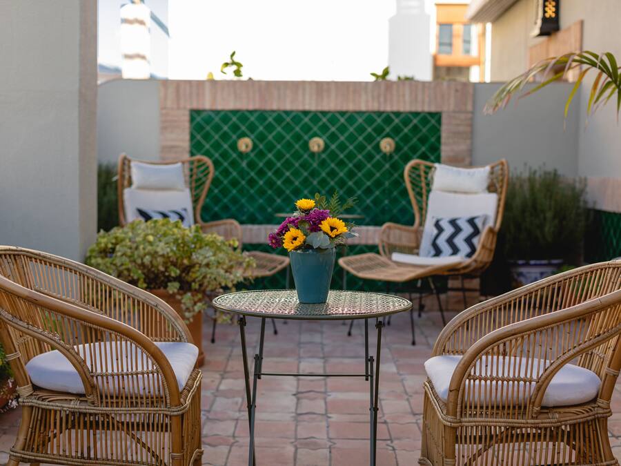 A patio area with wicker chairs, a small round table, and a vase of flowers.