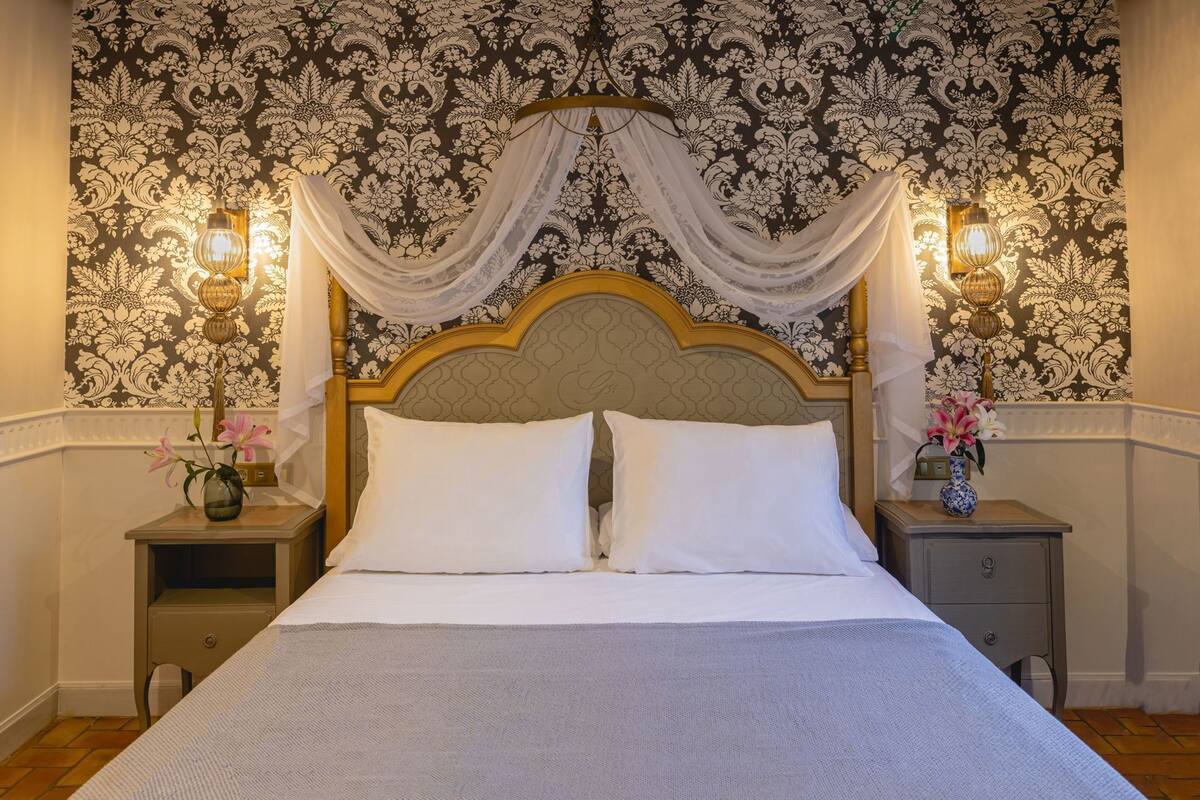 A bed with a wooden headboard, white bedding, and two bedside tables with lamps.