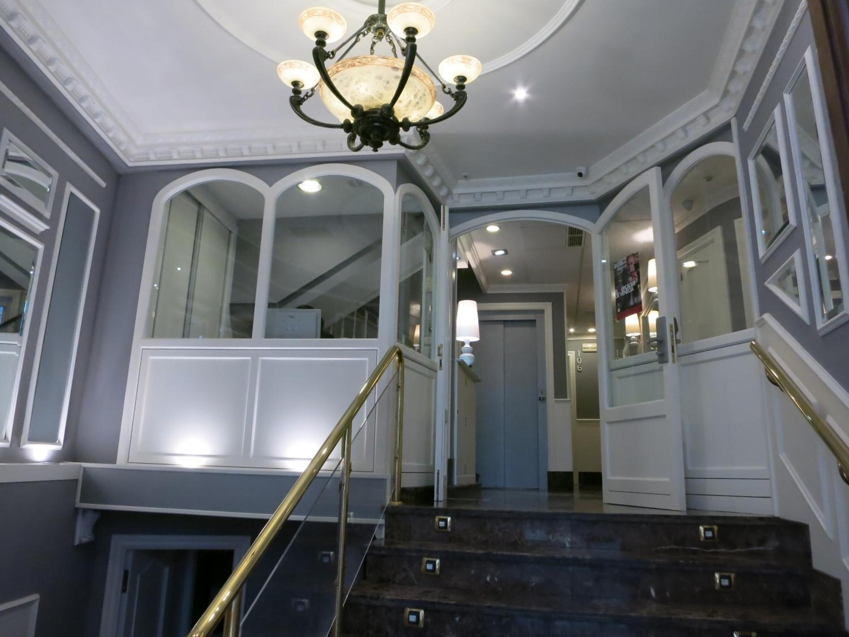 Un magnifique escalier, agrémenté d’un lustre, avec des murs blancs et un design moderne.
