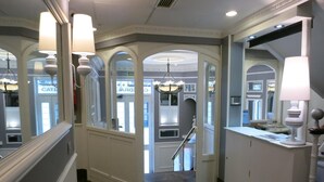 A hallway with a chandelier, a staircase, and a reception desk.
