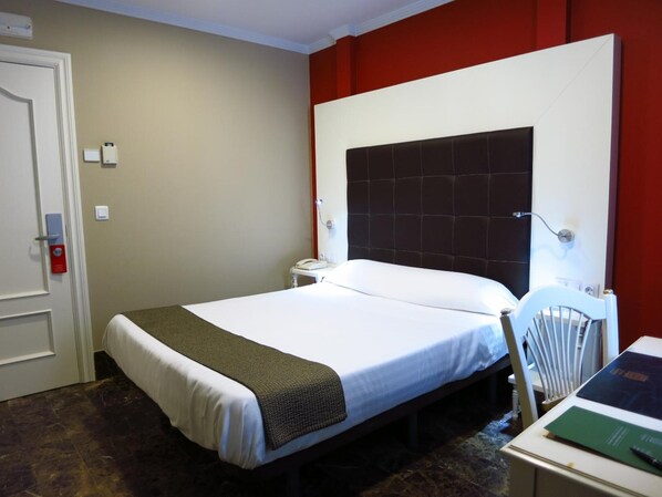 Une chambre d’hôtel avec un lit, une table de chevet et une chaise.