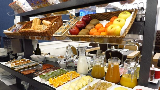 A buffet with various food items including fruits, bread, and beverages.