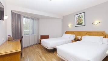 A hotel room with two beds, a desk, a chair, and a window with curtains.
