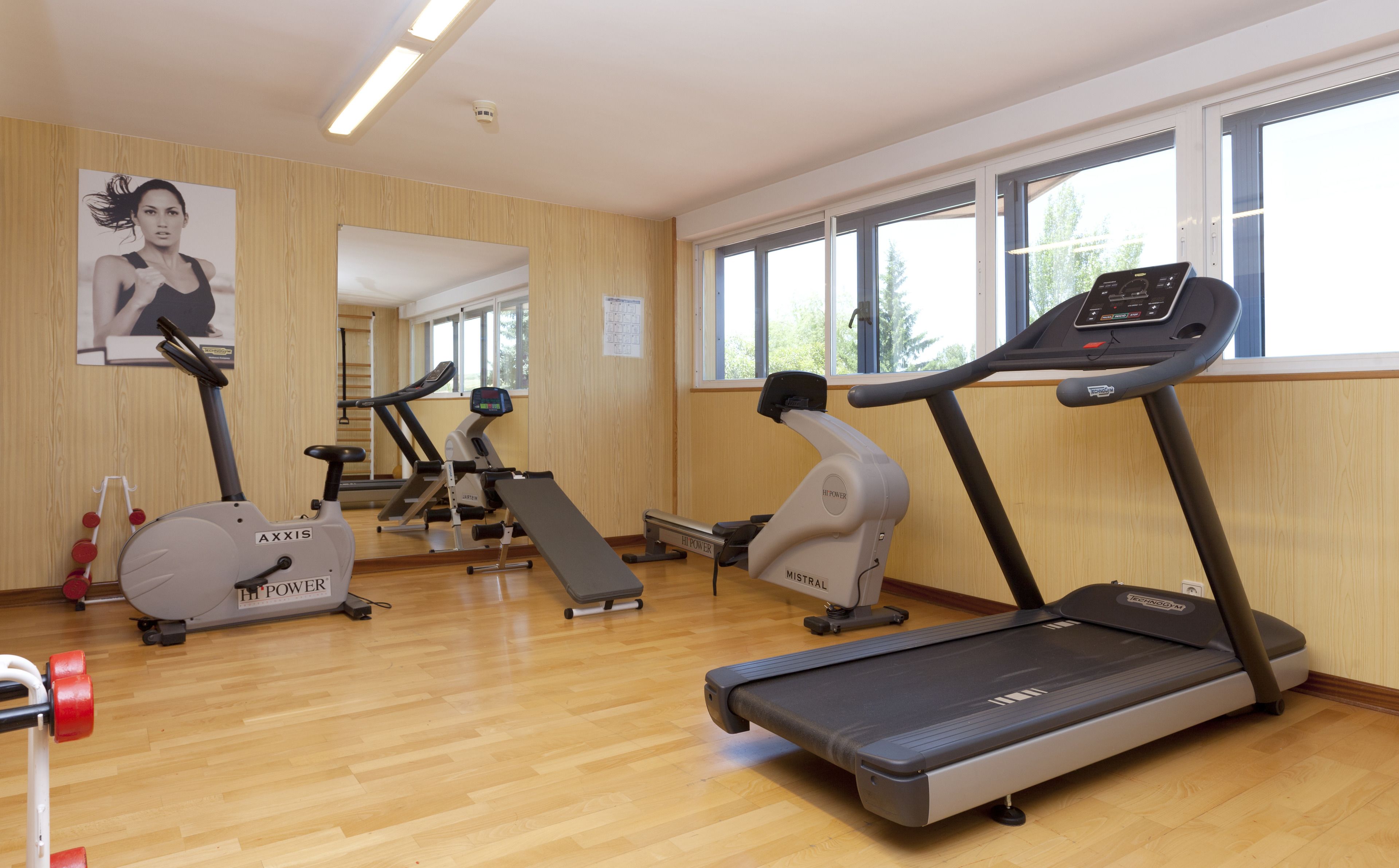 Un gimnasio con cintas de correr, elípticas y una bicicleta estática.