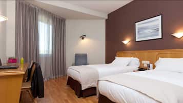 Habitación de hotel con dos camas, un escritorio con una computadora portátil, una silla y una ventana con cortinas.