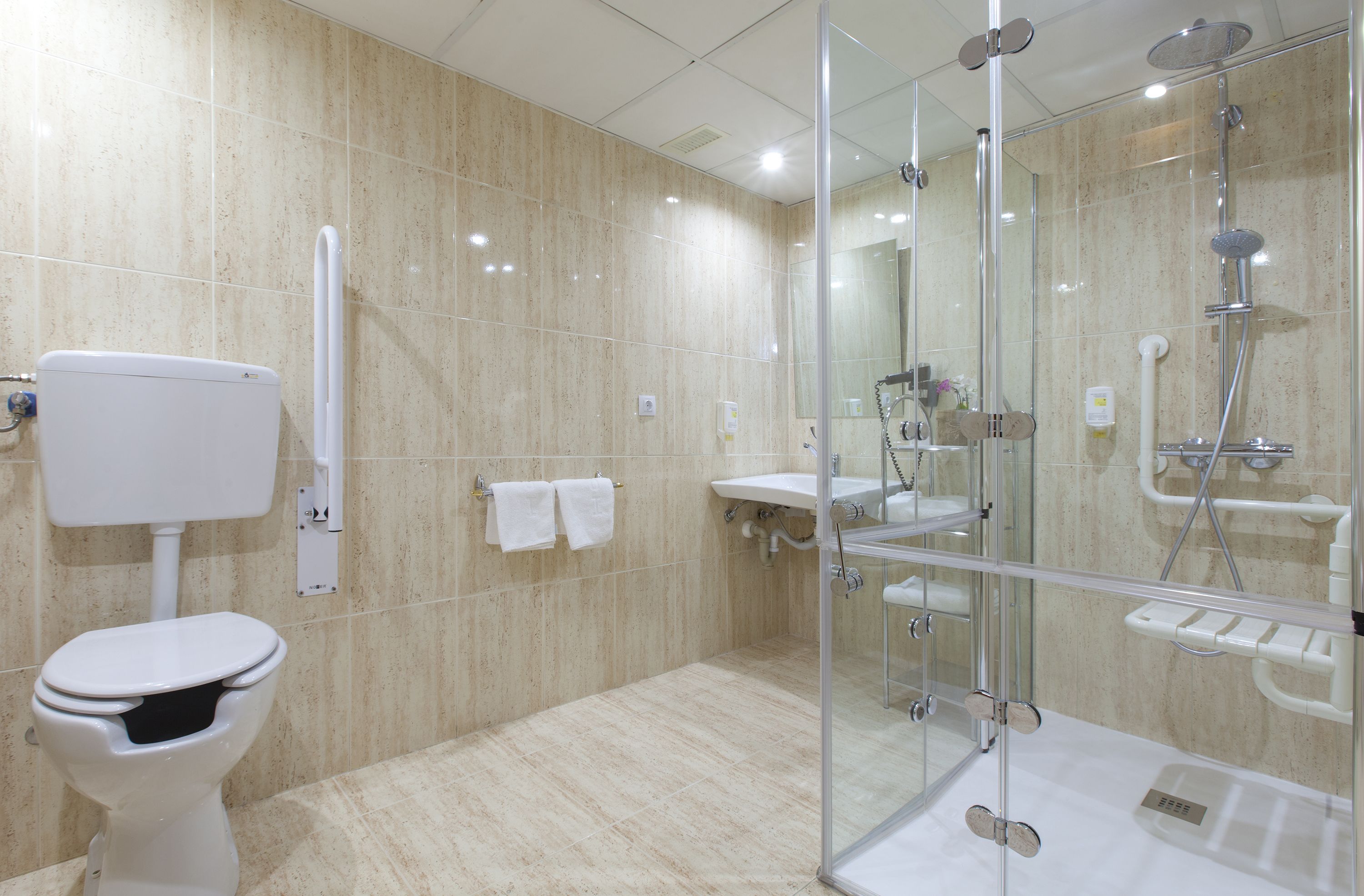 Un baño moderno con inodoro, lavamanos y cabina de ducha con mampara de vidrio.