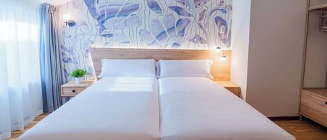 Cama doble con sábanas blancas, cabecera de madera y mesita de noche con una planta.