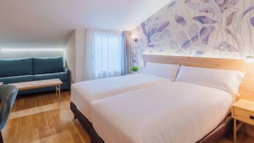Habitación de hotel con una cama grande, un sofá, una mesita y una pared decorada con arte abstracto.