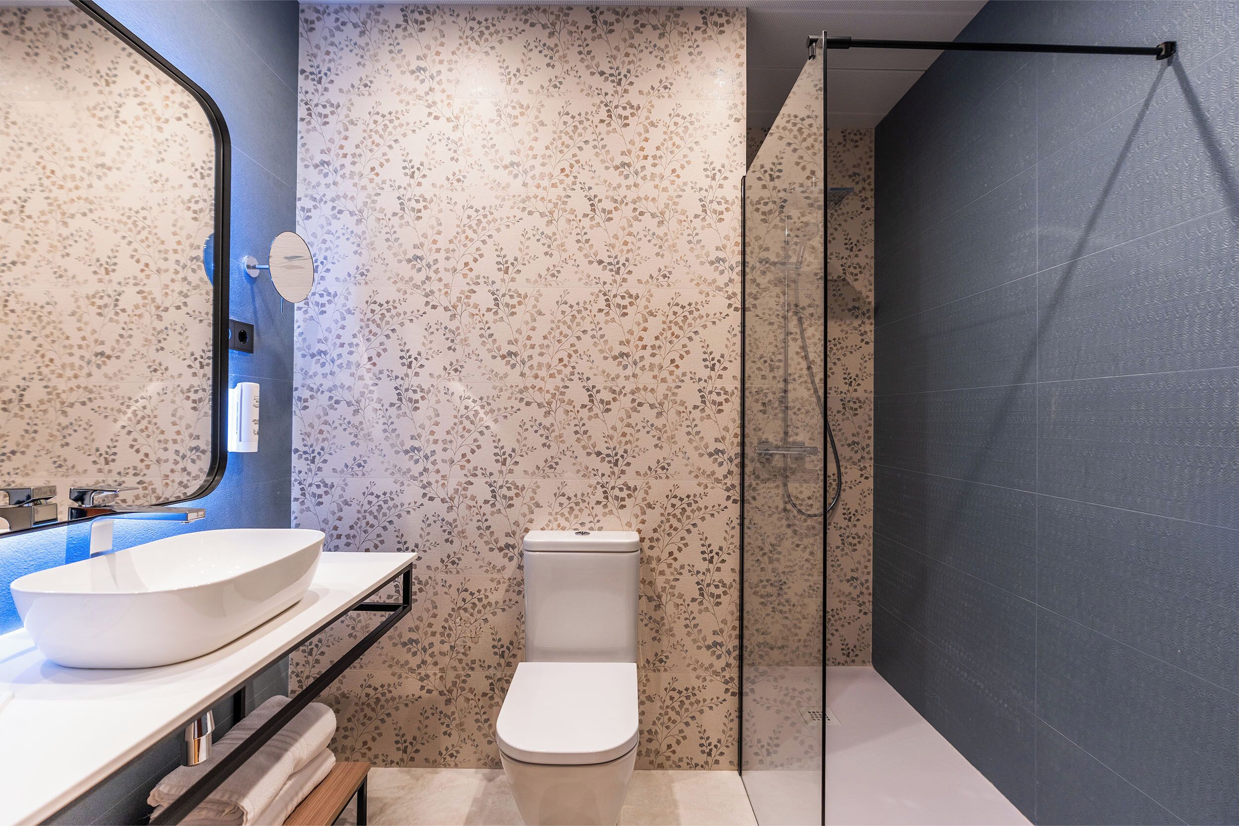 Ein modernes Badezimmer mit freistehender Toilette, einem großen Spiegel und einer Duschkabine.