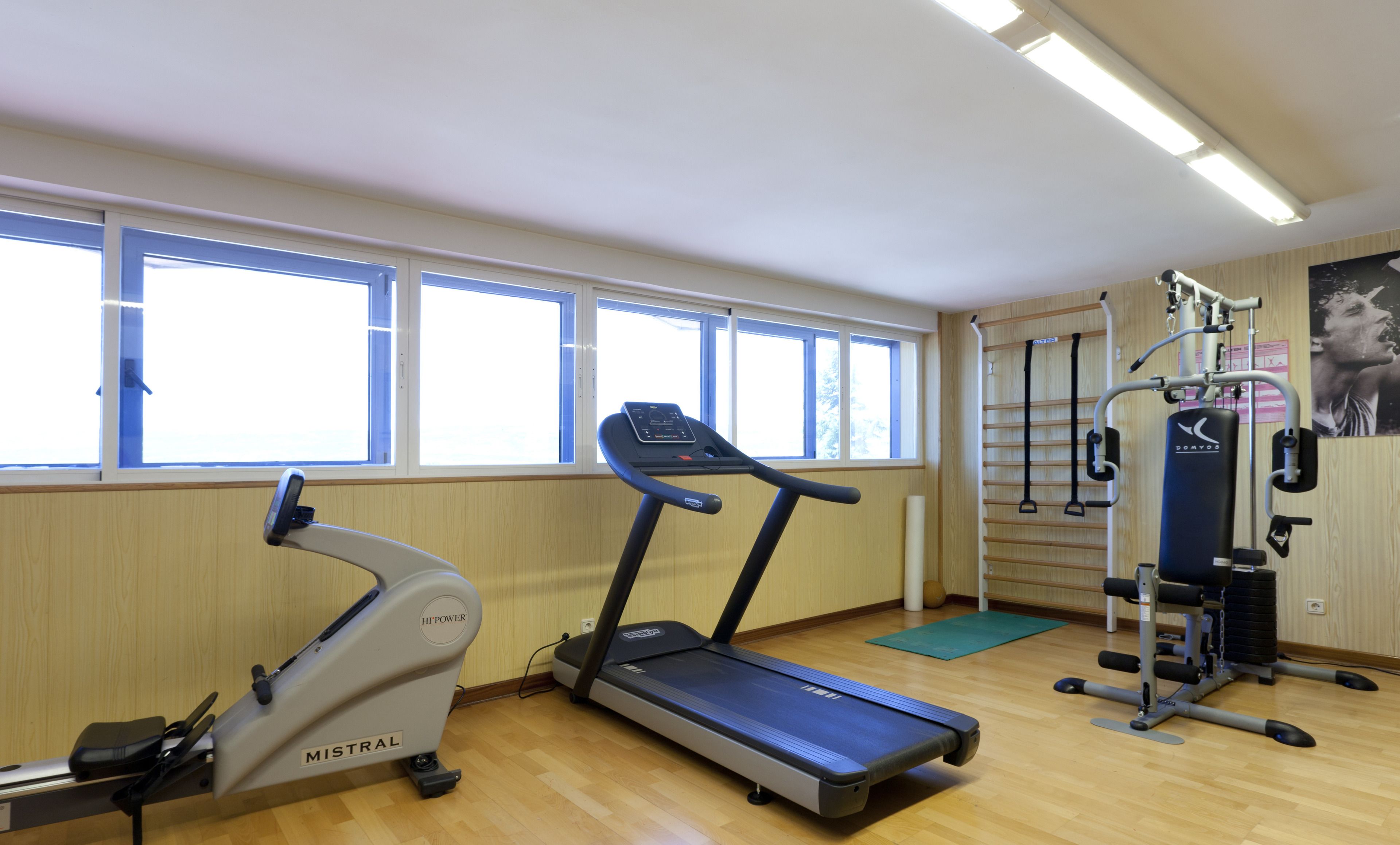 A gym with a treadmill, elliptical, and weight machines.