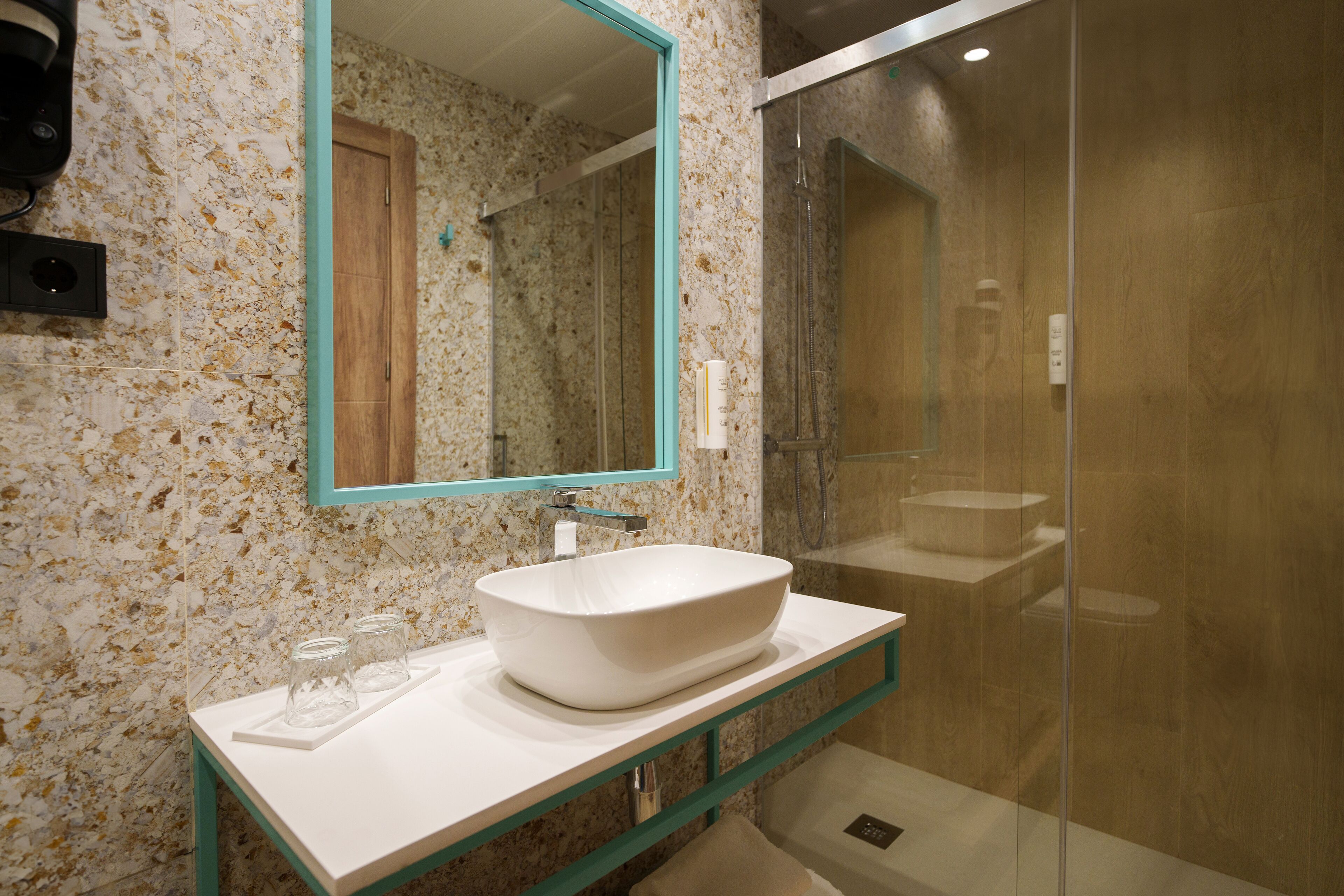 A bathroom with a white sink, a mirror, and a glass shower enclosure.