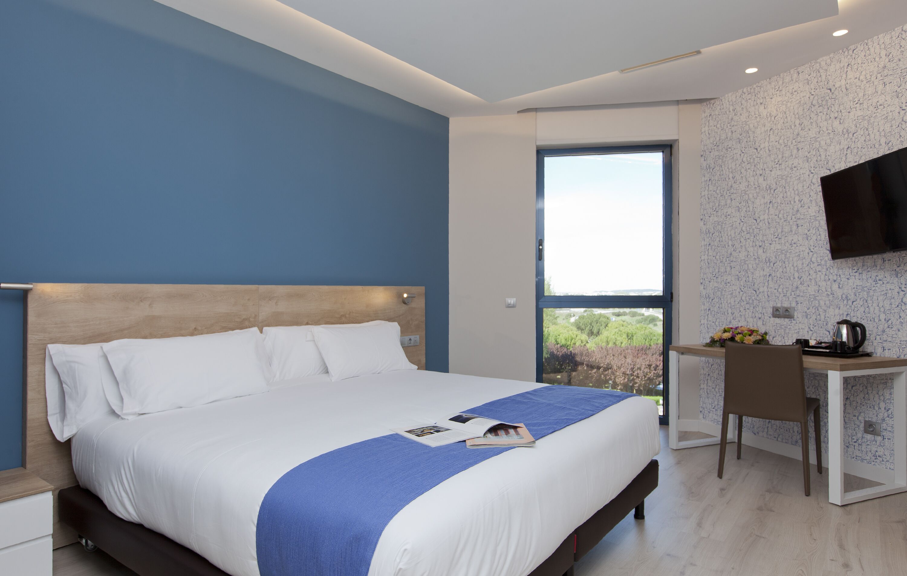 Una habitación de hotel moderna con una cama grande, un escritorio y un televisor.