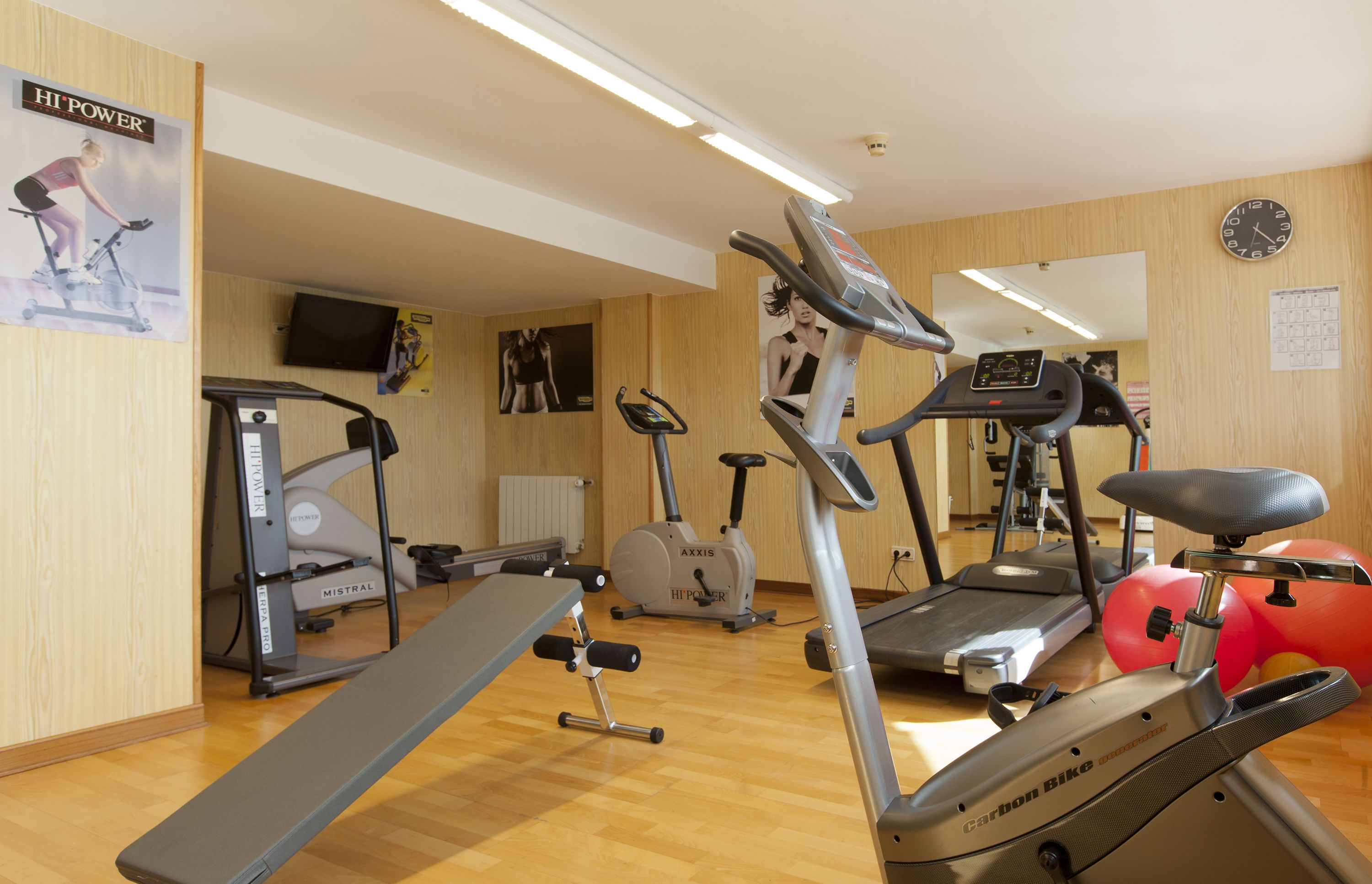 A gym with various exercise equipment including treadmills, stationary bikes, and weight machines.