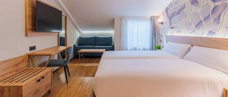 A hotel room with a large bed, a desk with a chair, a sofa, and a television mounted on the wall.