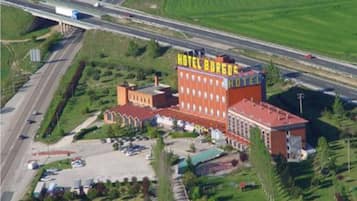 A hotel with a prominent sign, multiple buildings, a parking lot, and a highway in the background.