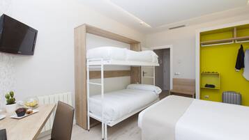 A bunk bed room with a desk, chair, and a TV mounted on the wall.