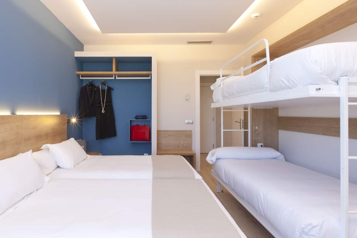 Habitación de hotel con dos camas, un armario y un espejo.
