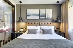 A hotel room with a large bed, two bedside tables, a nightstand, a wall-mounted artwork, and a window with curtains. - Hotel Cortes Rambla (Barcelona)