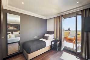 A hotel room with a large bed, a small table, and a view of the city through a sliding glass door. - Hotel Cortes Rambla (Barcelona)