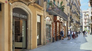 A hotel named 'Hotel Cortes' with a stone facade, large windows, and a visible entrance. - Hotel Cortes Rambla (Barcelona)