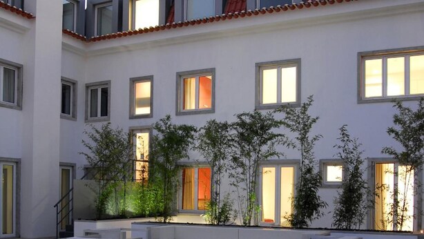 A rooftop terrace with outdoor seating, a pool, and a building with multiple windows and a red-tiled roof. - Hotel Jerónimos 8 (Lisbon)
