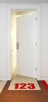 A hotel entrance with a door marked "123" and a lighted pathway leading to the interior.