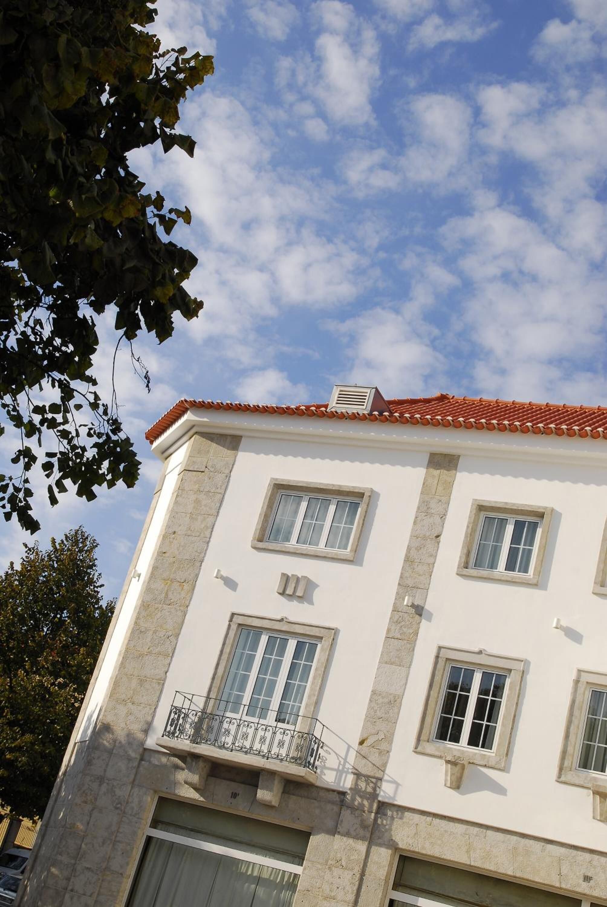 A two-story building with a red-tiled roof, white walls, and multiple windows.