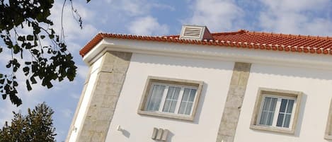 A two-story building with a red-tiled roof, white walls, and multiple windows.