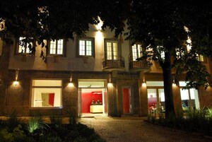 Egy kétszintes épület, amelyben recepció, erkély és vörös fényekkel megvilágított bejárat található.