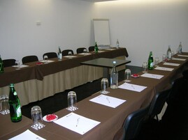 A conference room with long tables, chairs, water bottles, glasses, and nameplates.