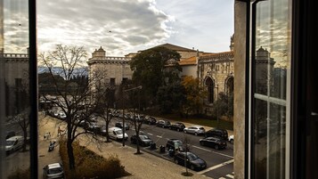 Vista de una calle con coches estacionados y un edificio histórico con tejado de baldosas.