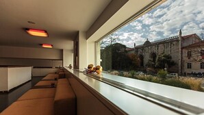 A modern hotel room with a long window, a sofa, and a view of a historic building. - Hotel Jerónimos 8 (Lisbon)