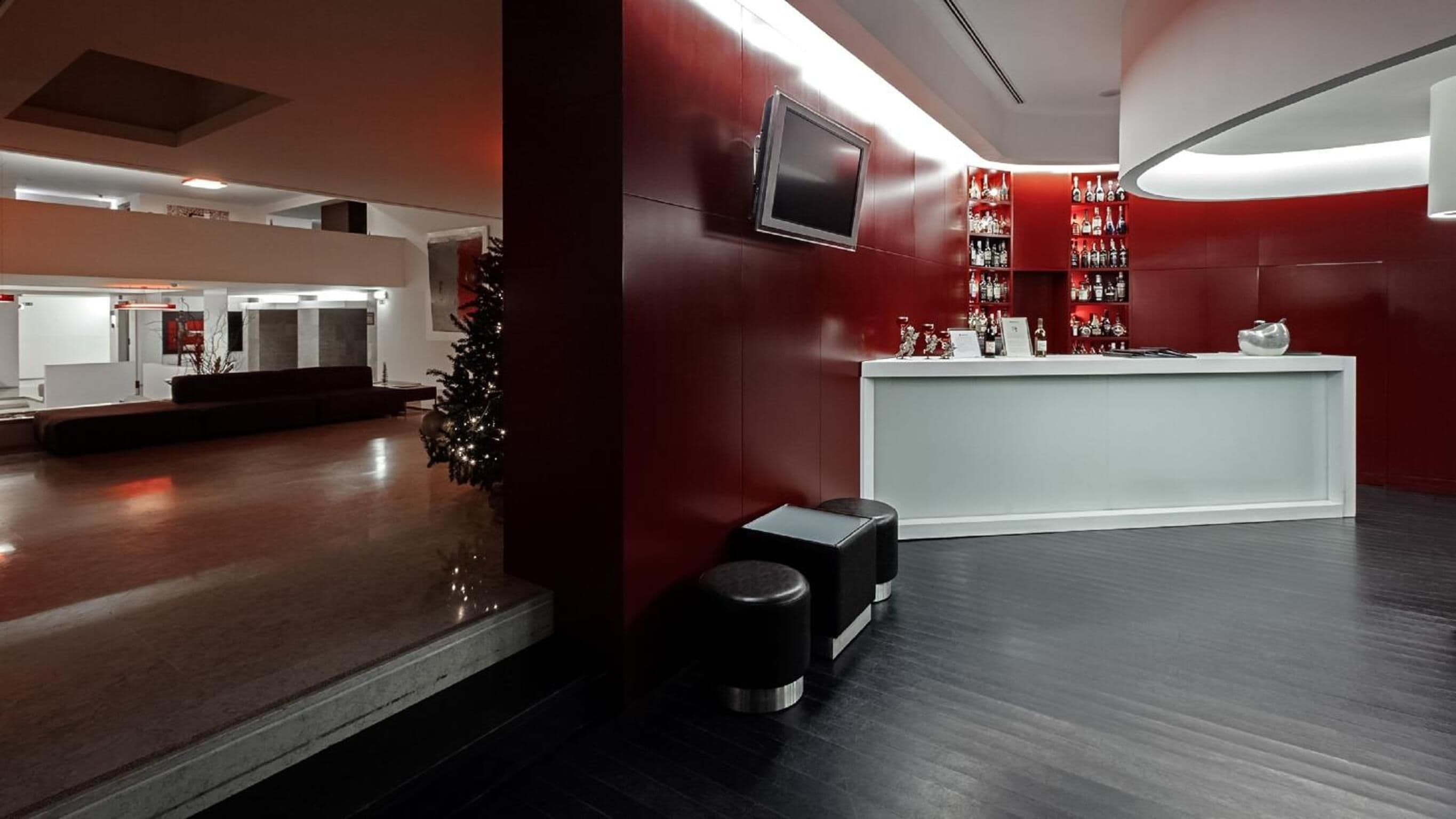 A modern lobby with a reception desk, a TV mounted on the wall, and a Christmas tree.