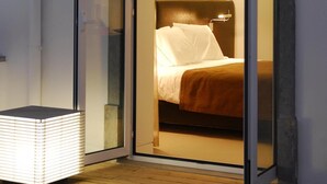 A modern hotel room with a glass door leading to a wooden deck. - Hotel Jerónimos 8 (Lisbon)