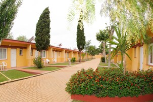Una hilera de edificios amarillos con puertas blancas, cada uno con un pequeño jardín y un camino pavimentado.